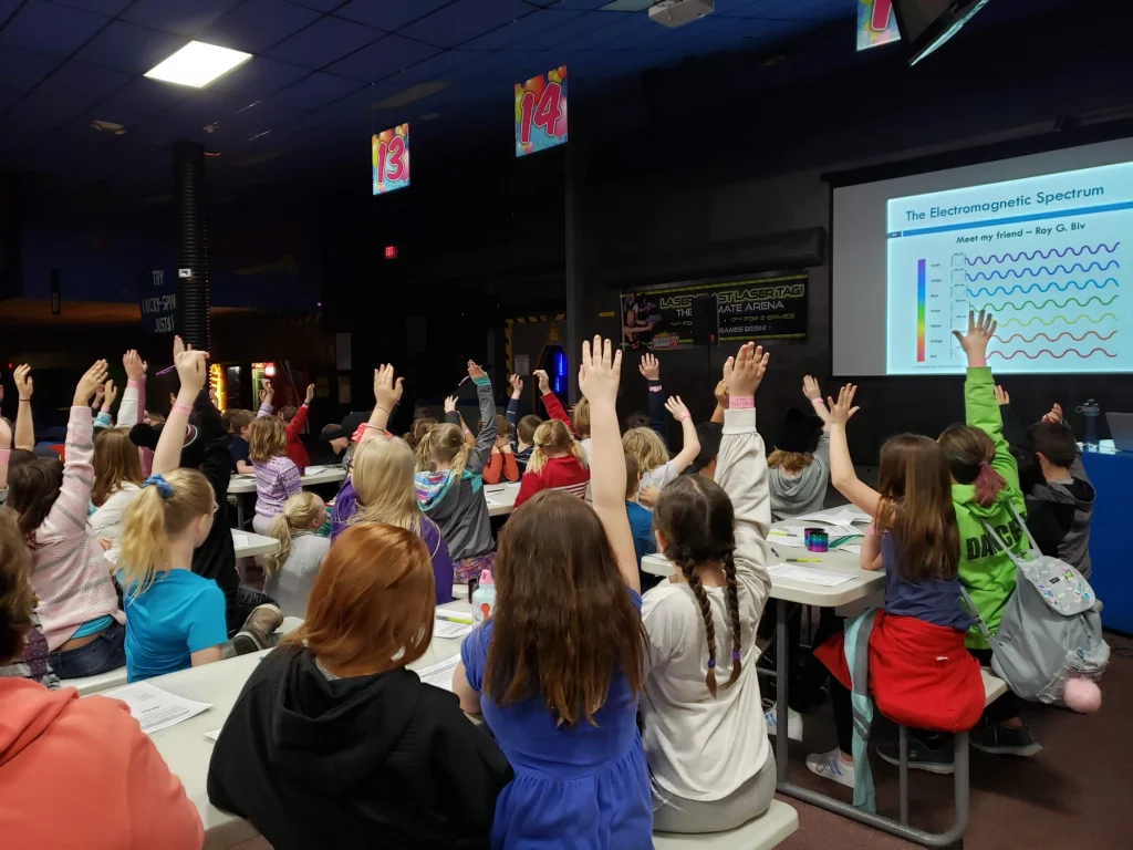 STEM teacher giving a lesson to a large field trip class at a roller skating rink