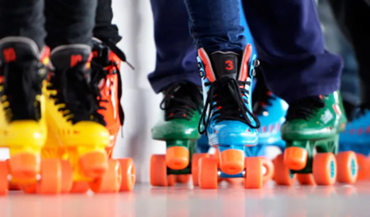 close up image of yellow, green, and blue roller skates on people's feet
