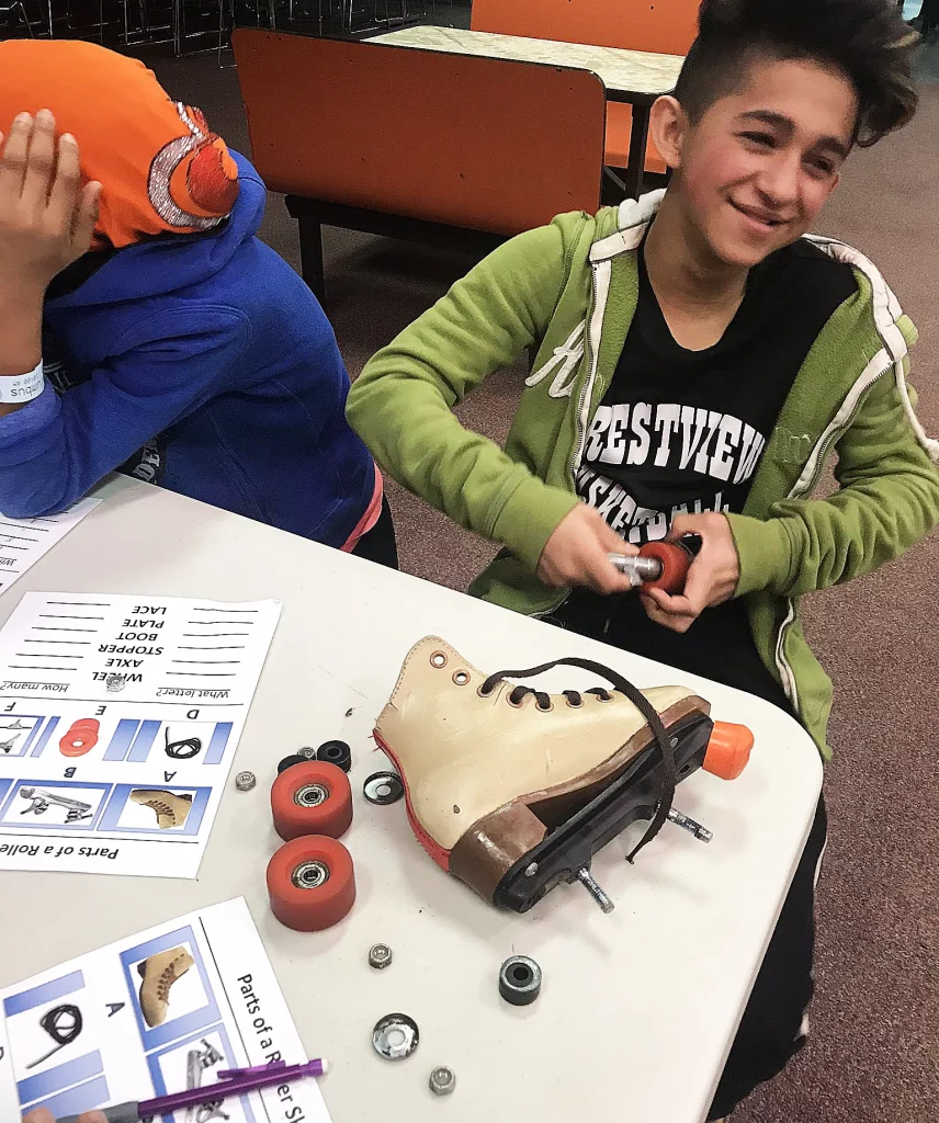 Two kids laughing while building a roller skate for a STEM project