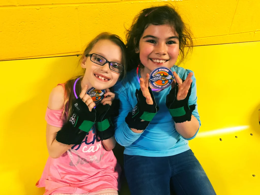 two girl scouts showing off their skating patches they earned