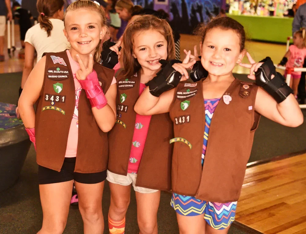 three girl scouts smiling and giving peace signs for the camera