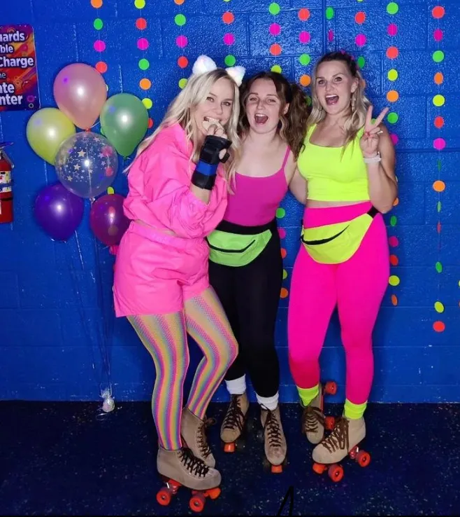 three women having fun dressed in neon clothing and smiling for the camera