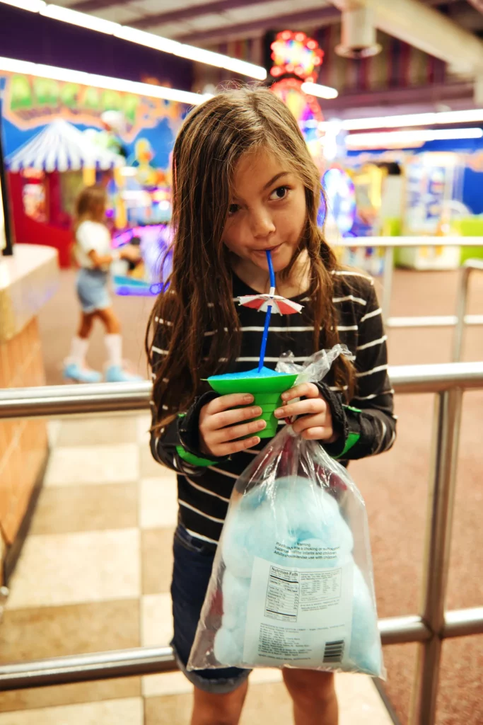 girl at the cafe drinking a blue icee and holding blue cotton candy