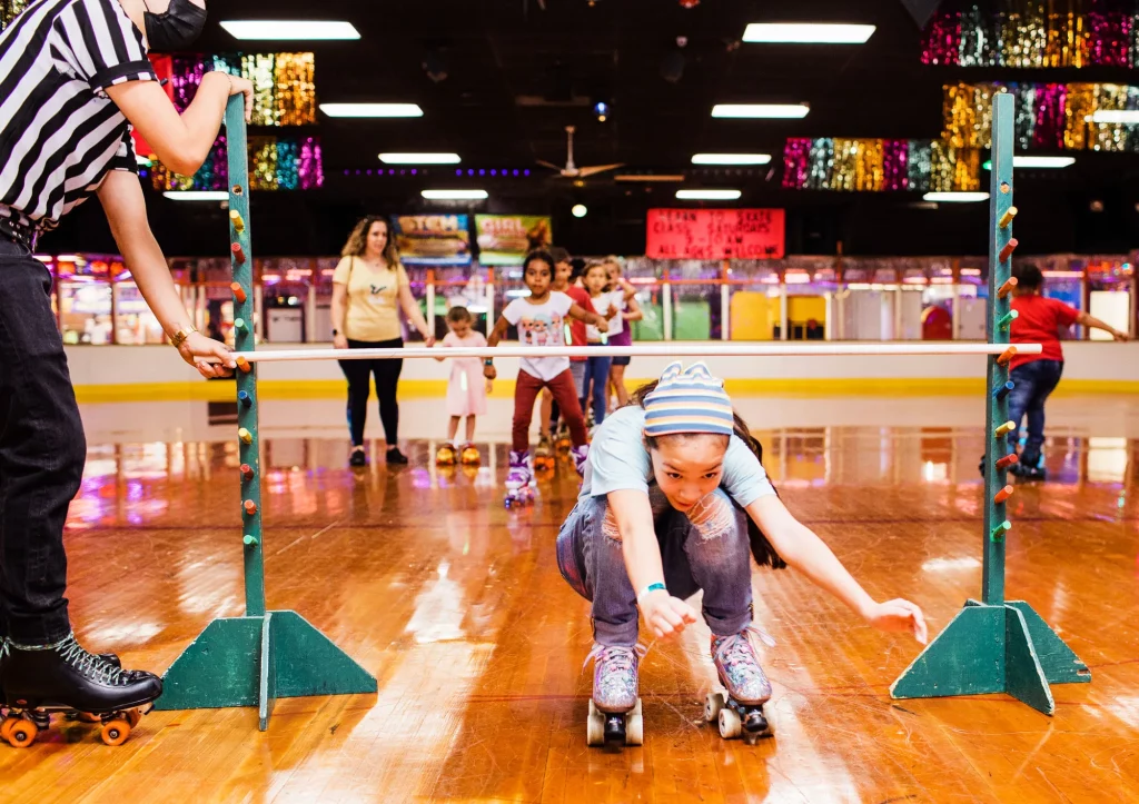 girl playing skate limbo and going underneath a pole