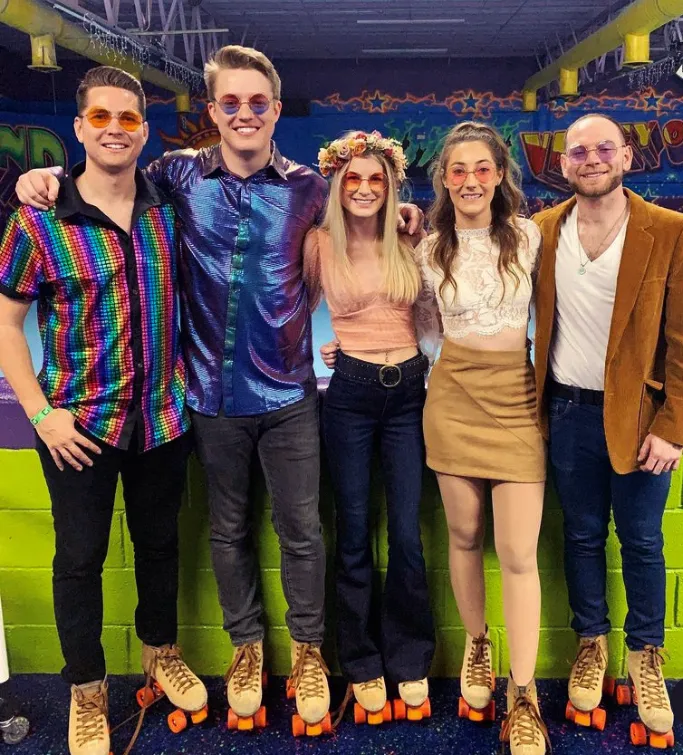 group of men and women dressed in 1960s hippie theme and roller skates