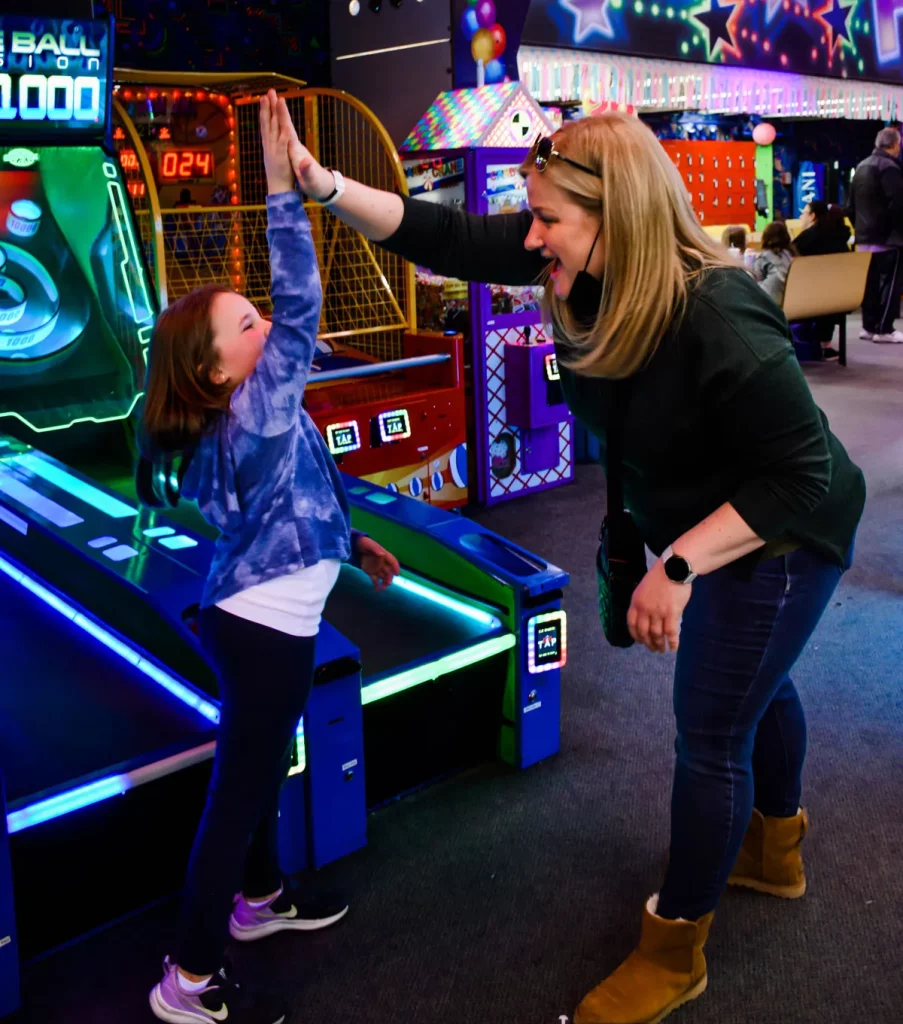 mom and daughter high-five at the skeeball machine